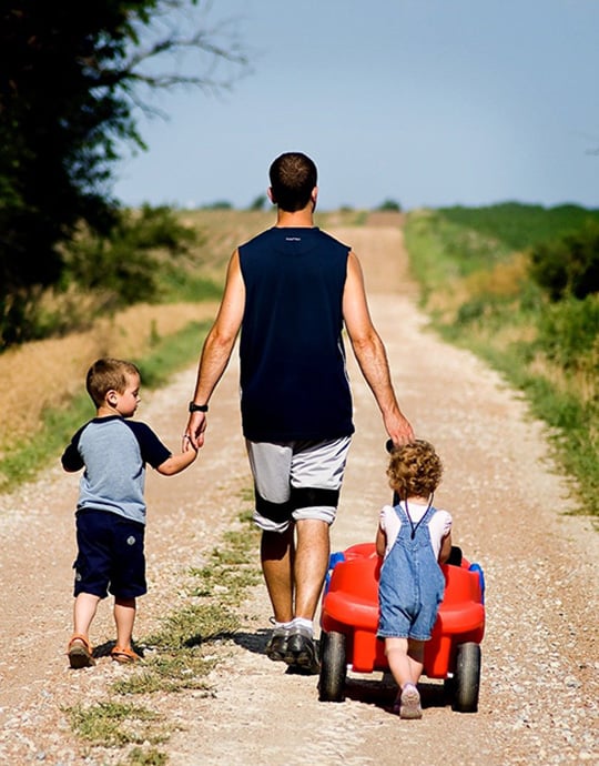 a father is walking with 2 children